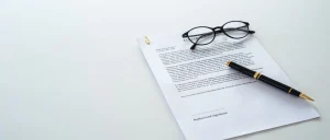 modelo de contrato hibrido em cima de uma mesa branca com um óculos e uma caneta ao lados dos papeis