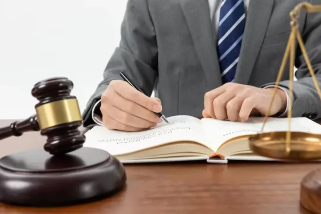 Pessoa de terno assinando um contrato ao lado de uma balança de justiça e um martelo de juiz, simbolizando autonomia jurídica e papel de advogado.